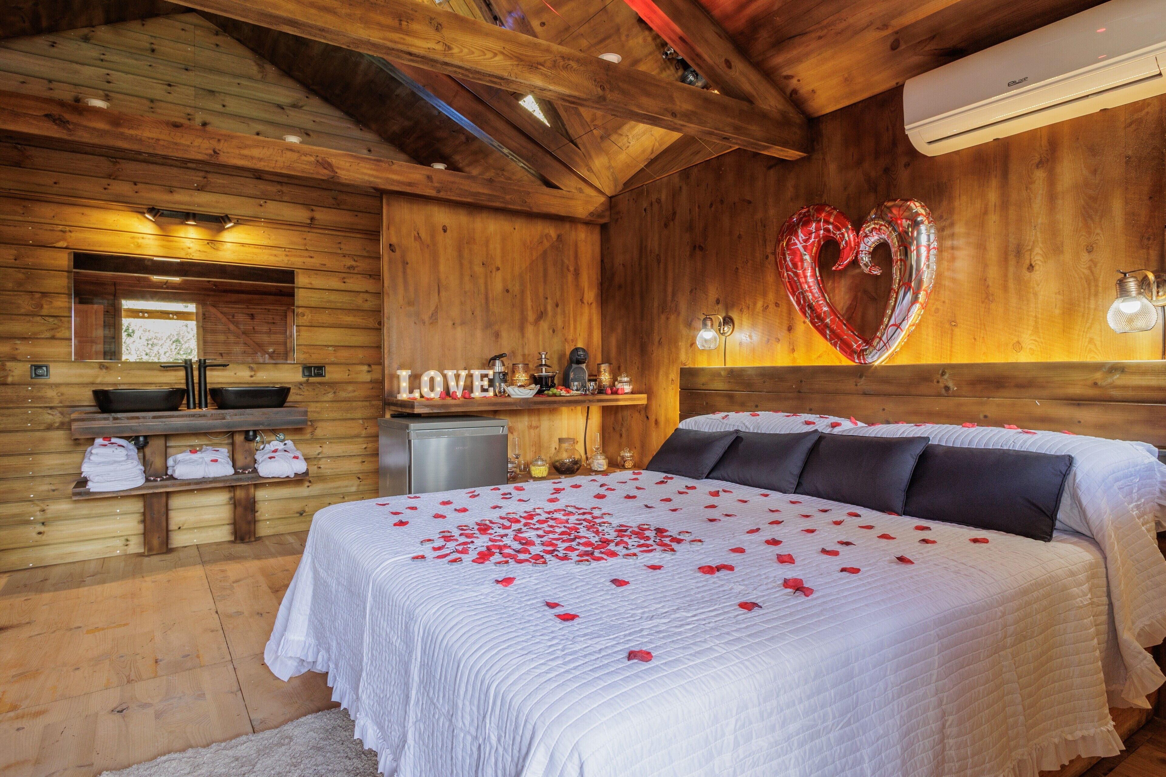 Een houten kamer met een bed, een hartvormige ballon en een ‘LOVE’ bord.