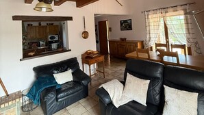 A spacious living area with a high wooden ceiling, a black leather sofa, a dining table, and a kitchen visible through an open doorway. - Chez Polo - House with swimming pool in Vallon-Pont-d'Arc (Vallon-Pont-d'Arc)