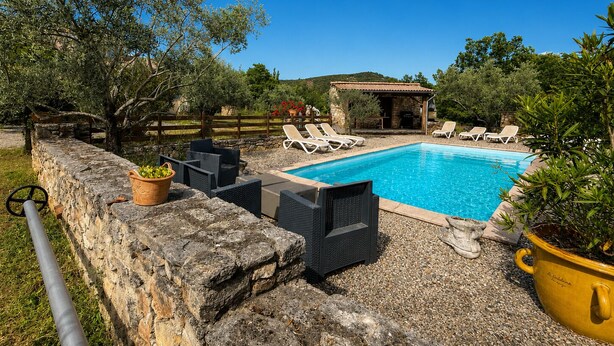 A swimming pool with lounge chairs, a stone wall, and a stone building in the background. - Chez Polo - House with swimming pool in Vallon-Pont-d'Arc (Vallon-Pont-d'Arc)