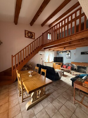 A spacious living area with a wooden staircase, a dining table, and a fireplace. - Chez Polo - House with swimming pool in Vallon-Pont-d'Arc (Vallon-Pont-d'Arc)
