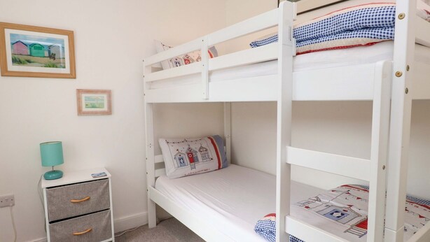 Una stanza con un letto a castello, un comodino, una lampada e due quadri appesi al muro.