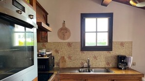Uma cozinha com armários de madeira, forno embutido, uma janela e uma cafeteira.