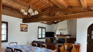 Uma sala de jantar com teto de madeira, uma mesa com colcha e cadeiras.