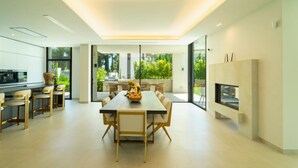 A modern kitchen with a dining area, large windows, and a fireplace. - Luxury villa with sea view - 10 guests (Marbella)