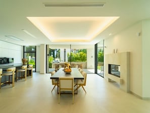 Eine moderne Küche mit Essbereich, großen Fenstern und einem Kamin.