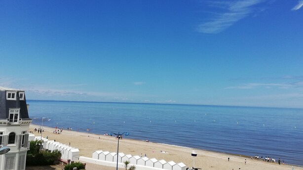 A beach with a row of white beach huts, a clear blue sky, and calm sea. - 3 beautiful sea views (Villers-sur-Mer)