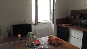A kitchen with a dining table set for two, a TV, and a window with a view. - 3 beautiful sea views (Villers-sur-Mer)