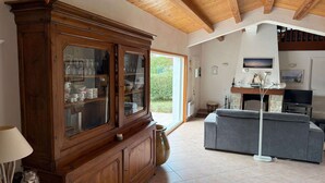Ein Wohnzimmer mit einem Holzschrank, einem grauen Sofa, einem Fernseher und einem Kamin.
