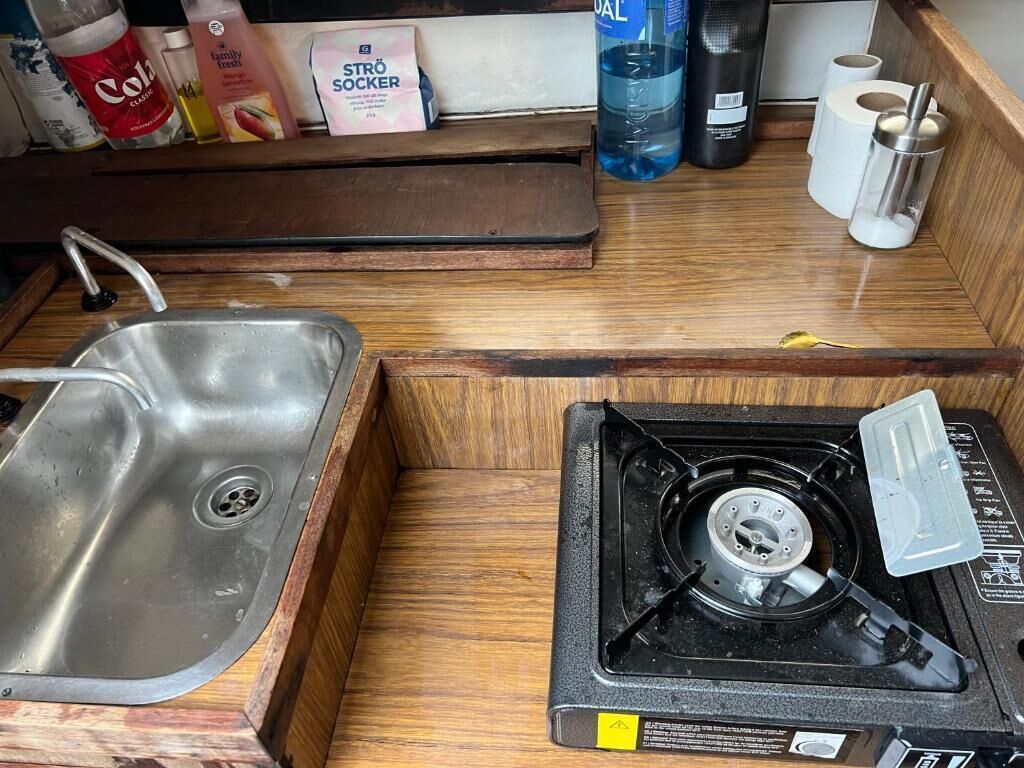 A kitchenette with a sink, stove, and storage for toiletries.