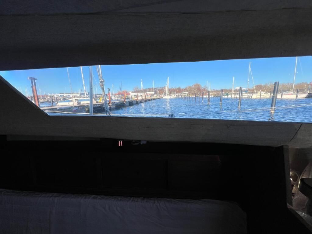 A view from a boat's cabin with a skylight, a marina with boats, and a clear sky.