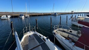 A marina with boats docked at wooden piers, clear skies, and calm water.
