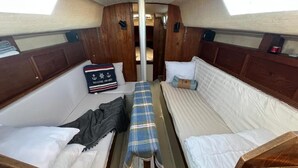A cabin with two beds, a bench, and a wooden headboard.