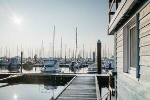 Una marina con barcos amarrados, un muelle de madera y un edificio con ventanal.
