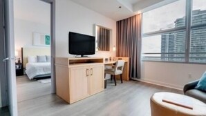 Ein modernes Hotelzimmer mit Bett, Schreibtisch, Fernseher und großem Fenster mit Blick auf die Stadt.