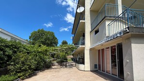 A building with a paved courtyard, a satellite dish, and a balcony with a railing. - Apartman Karlo  (Crikvenica)
