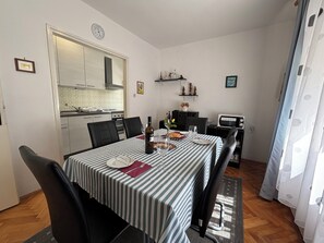 Ein Essbereich mit gestreiftem Tischläufer, Stühlen, einer Weinflasche und einer Mikrowelle.