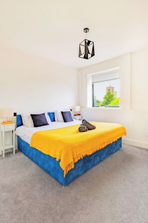Ein Schlafzimmer mit Bett, Fenster, Nachttisch und Lampe.
