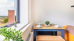 A balcony with a dining table set, a potted plant, and a view of the cityscape. - Stylish Central Location Apartment (Norwich)