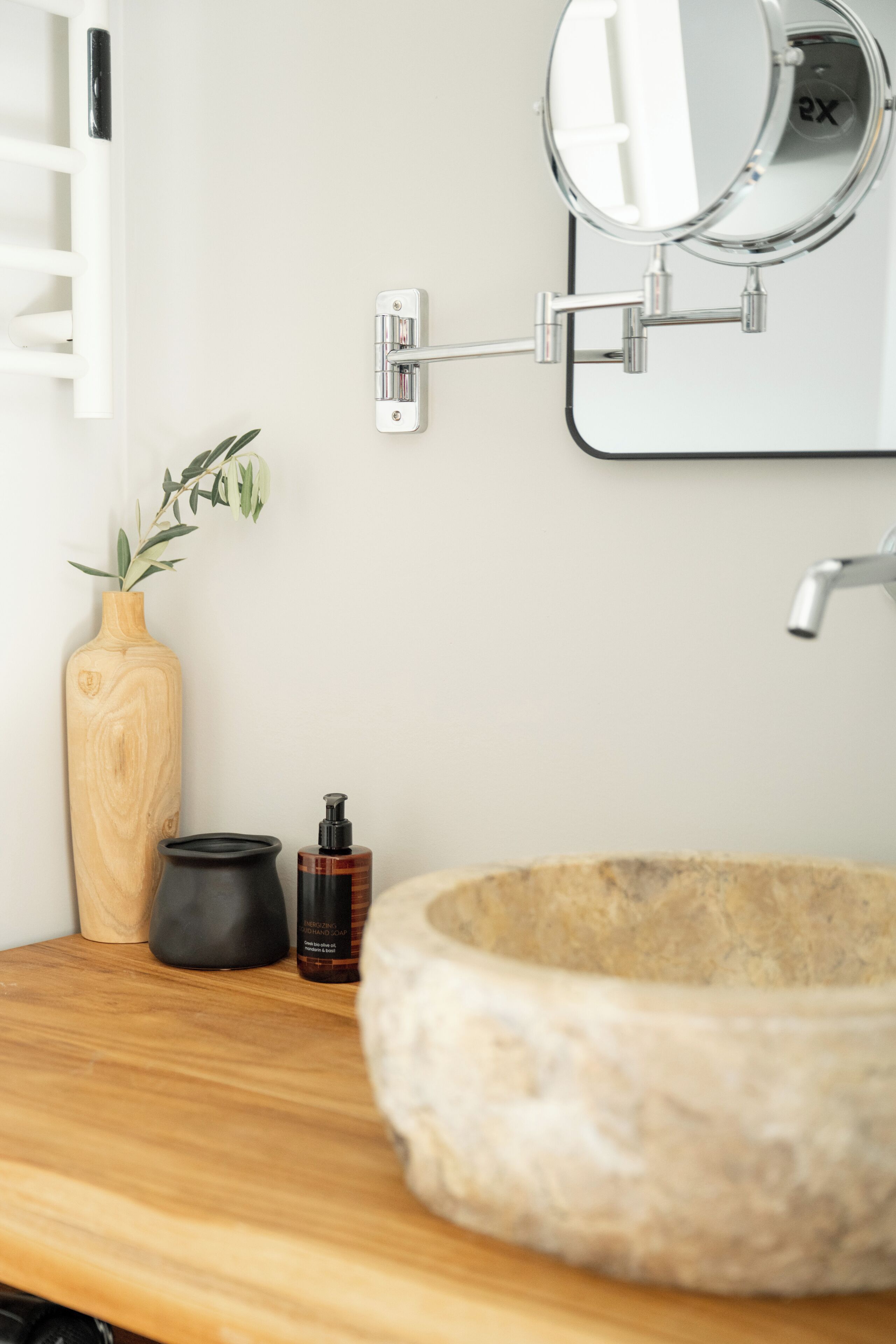 Ein Badezimmer mit einem Holzkosmetikschrank, einem Steinsink, einem Spiegel und einer kleinen Pflanze.