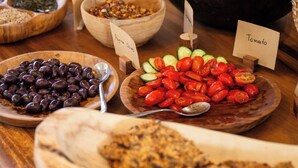 A variety of food items displayed on a wooden table with labels indicating different types of food. - Seagonia (Aktio-Vonitsa)