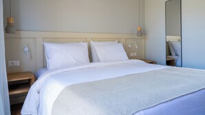 A neatly made bed with white bedding, a bedside table, a wall-mounted lamp, and a mirror. - Seagonia (Aktio-Vonitsa)
