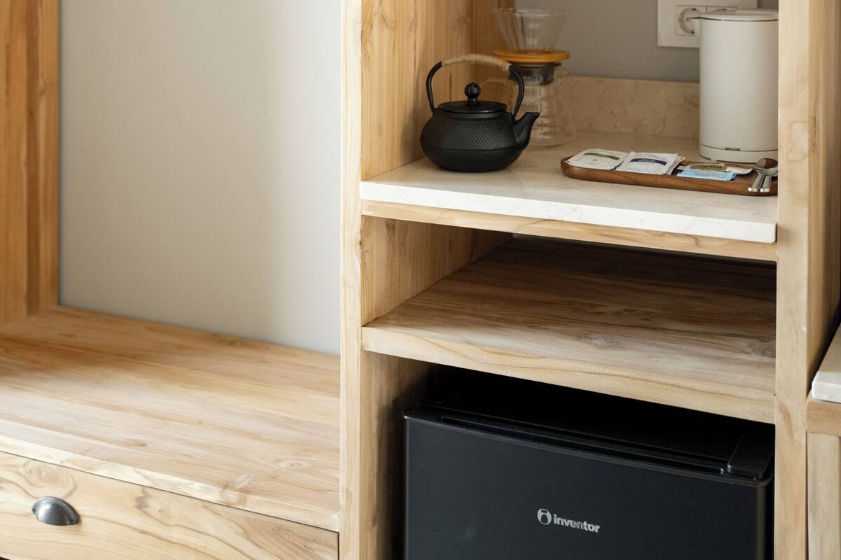 A wooden shelving unit with kitchenware, a kettle, and a coffee maker.