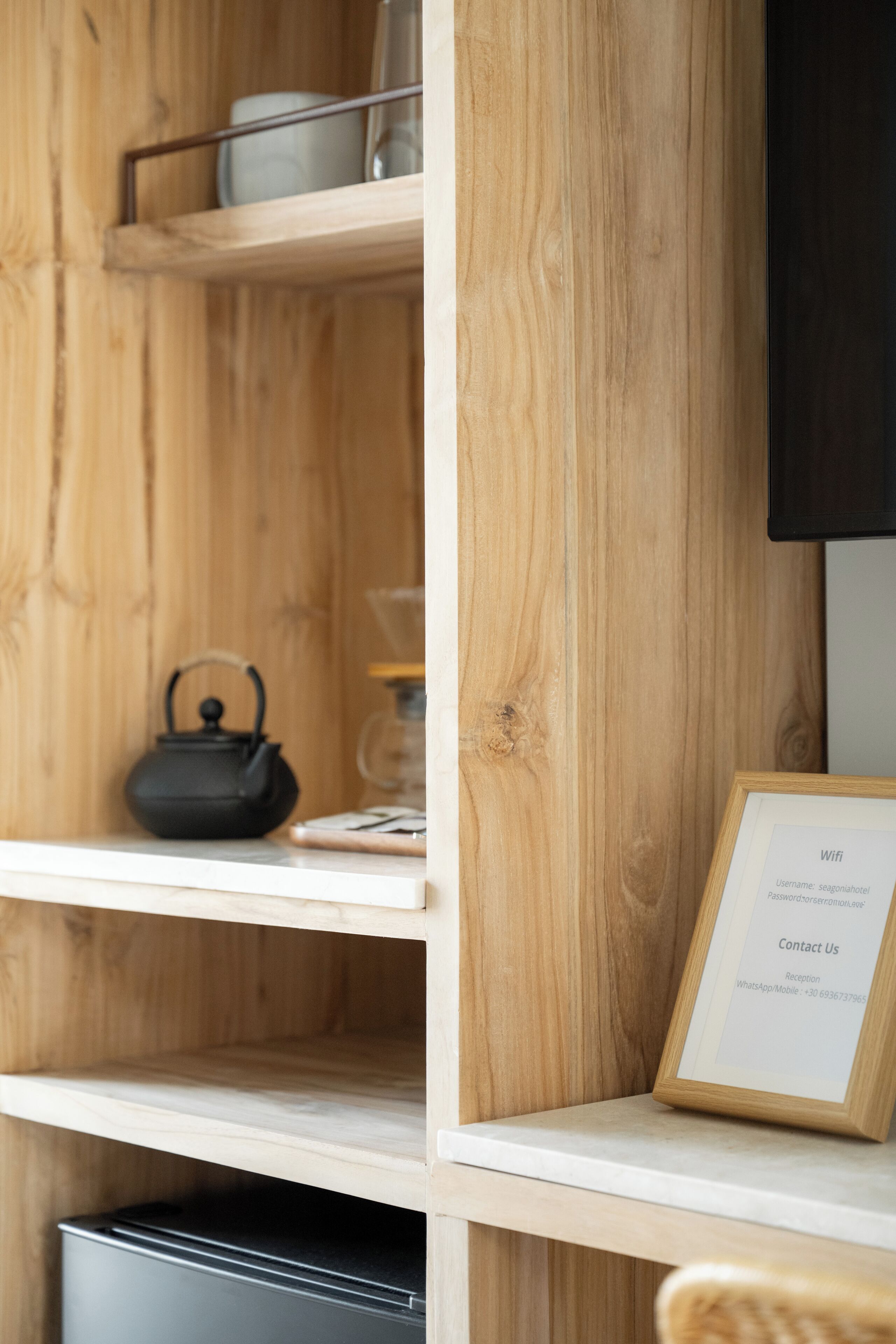 Een houten plank met een waterkoker, een ingelijst document en een glazen pot.
