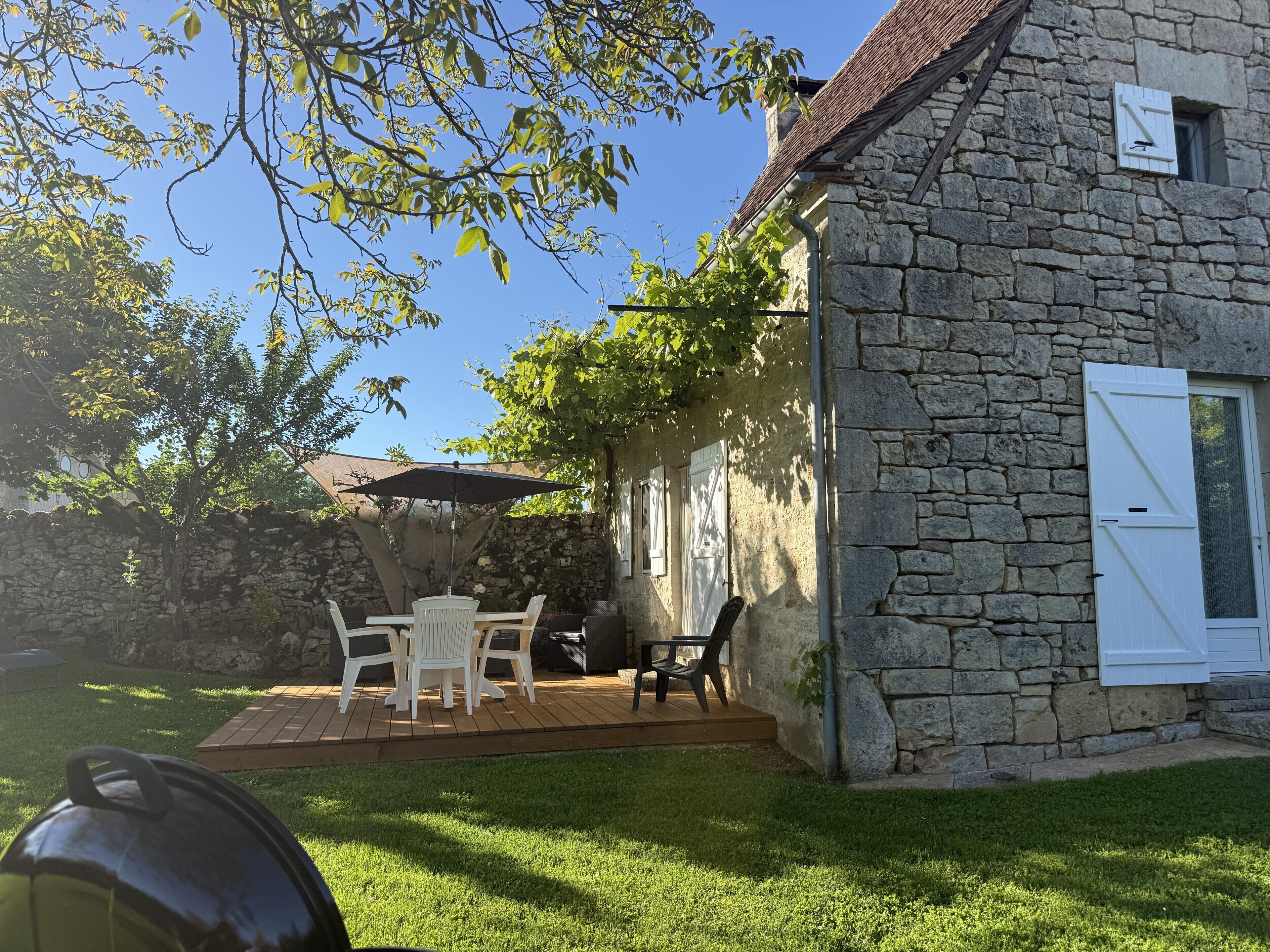A stone house with a patio, outdoor seating, and a covered area.