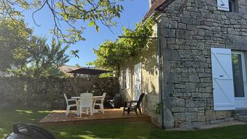 A stone house with a patio, outdoor seating, and a covered area.