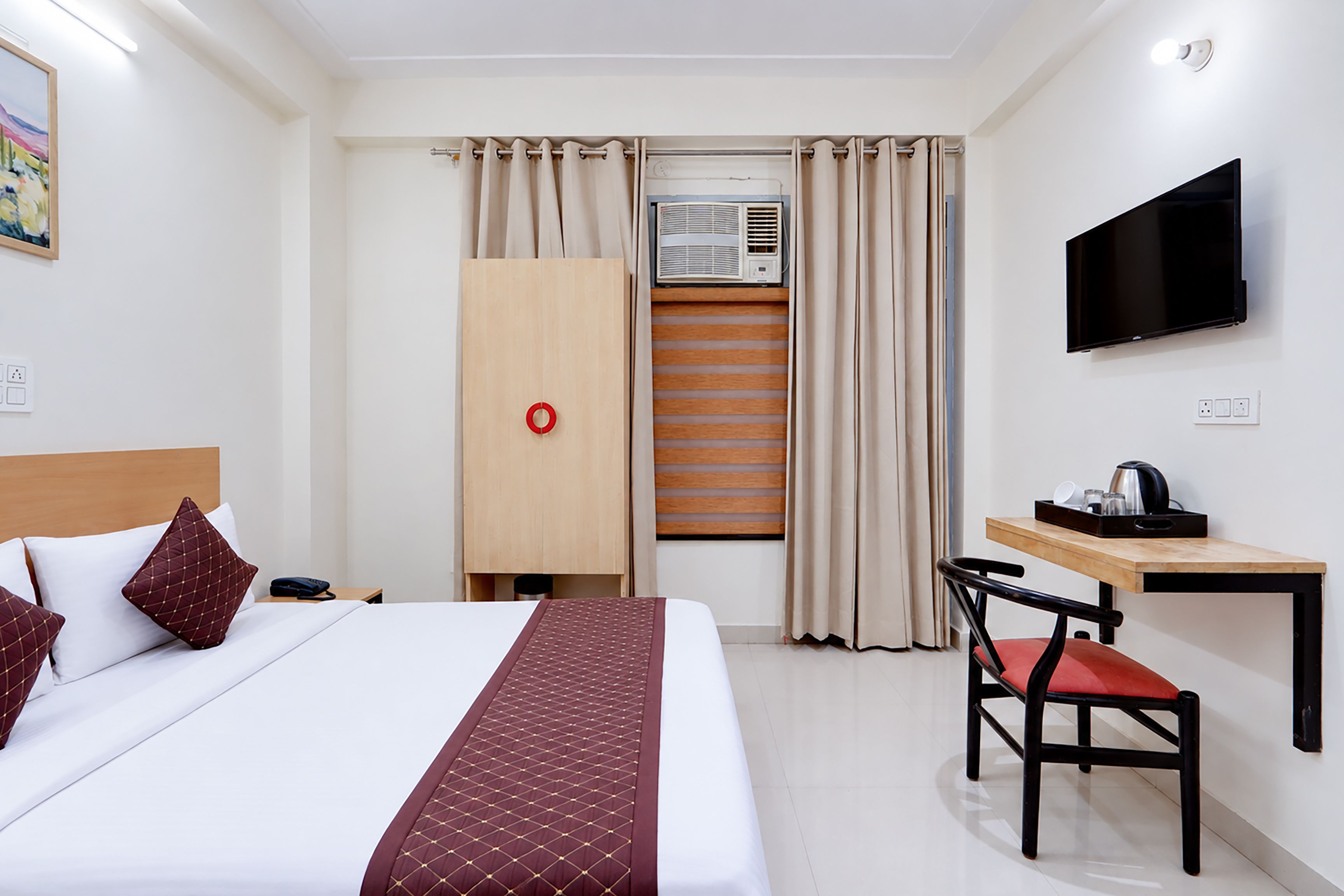 Une chambre d’hôtel équipée d’un lit, d’un bureau, d’une chaise, d’une télévision et d’un appareil de climatisation.