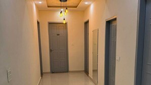 A hallway with a tiled floor, a ceiling light fixture, and doors on both sides. - Cloud Bay Hotels - Sector 69 (Gurugram)