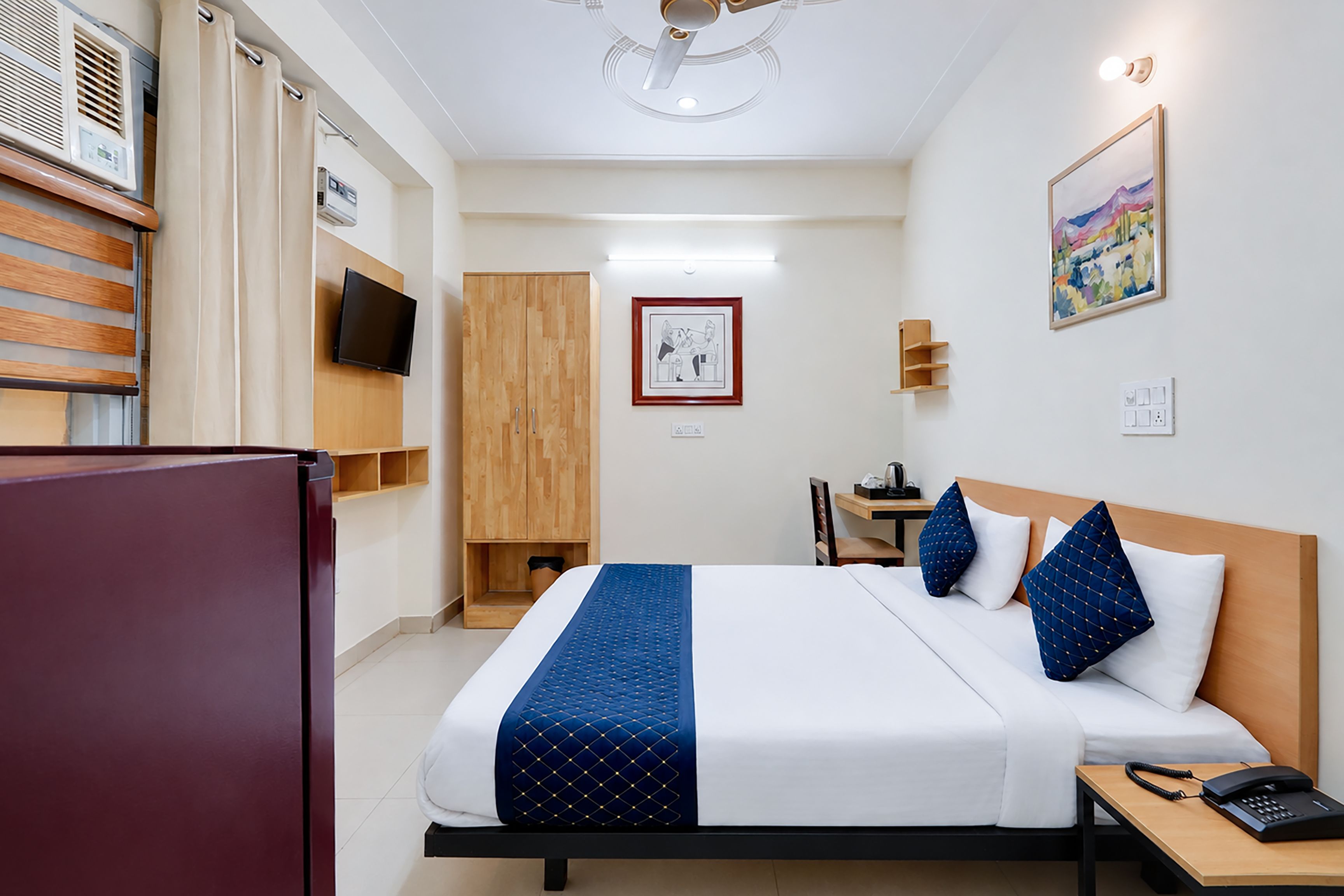 Une chambre d’hôtel comprenant un lit, un bureau, une chaise, une télévision et une armoire.