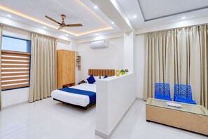 A modern hotel room with a bed, a desk, a wardrobe, and a ceiling fan. - Cloud Bay Hotels - Sector 69 (Gurugram)