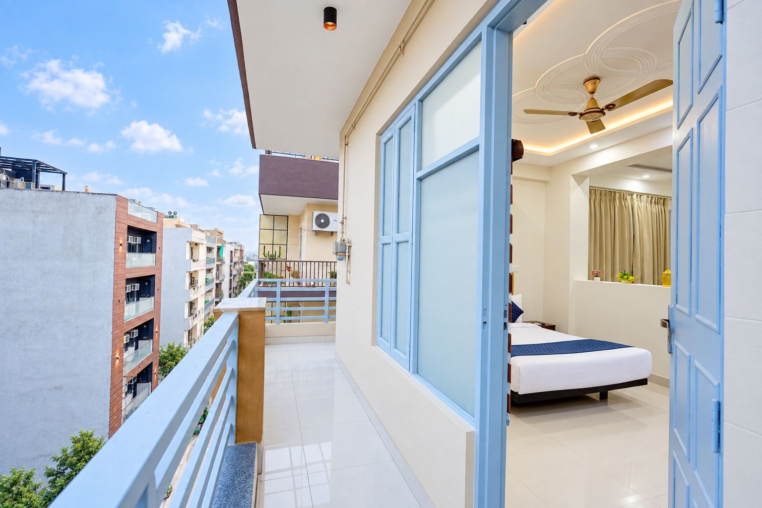 A modern hotel room with a balcony, a ceiling fan, and a bed.