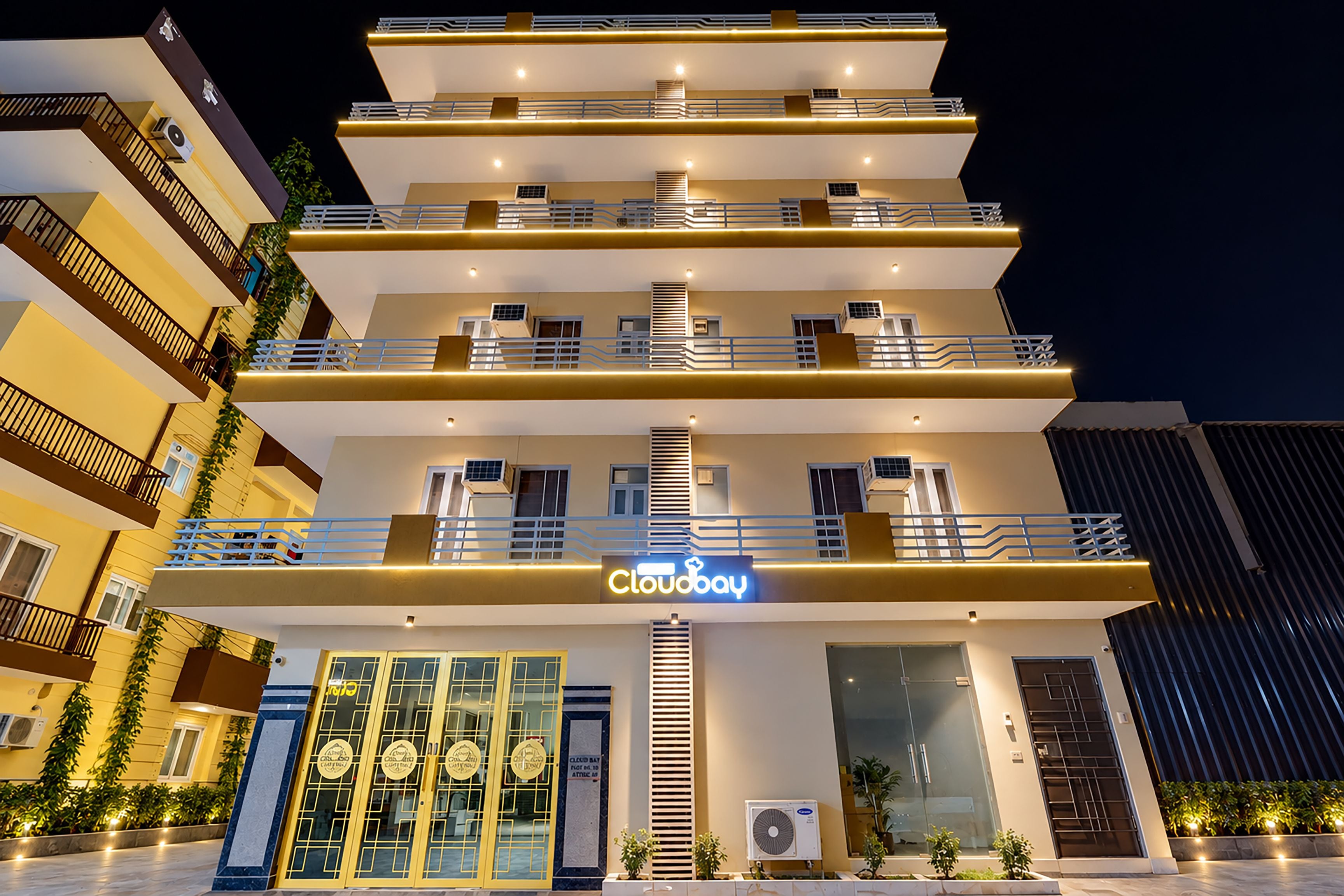 Un hotel de varios pisos con un llamativo letrero 'Cloudbay', balcones y un diseño arquitectónico moderno.