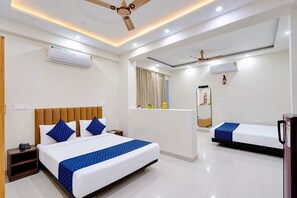 A hotel room with a large bed, a smaller bed, a wardrobe, a desk, a mirror, and a ceiling fan. - Cloud Bay Hotels - Sector 69 (Gurugram)