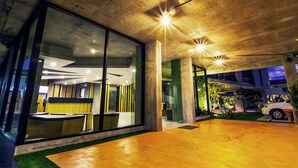 Un edificio moderno con amplios ventanales de vidrio, techo de concreto y un interior bien iluminado.