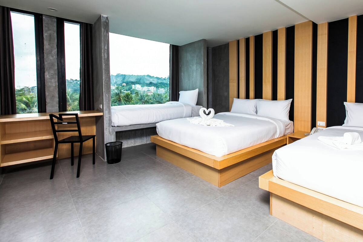 Habitación de hotel con dos camas, un escritorio y vista a zonas verdes.