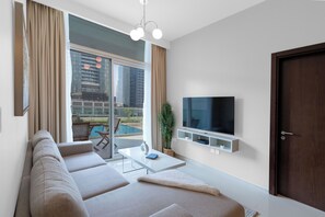 Ein modernes Wohnzimmer mit einer Couch, einem Fernseher und Blick auf einen Swimmingpool.
