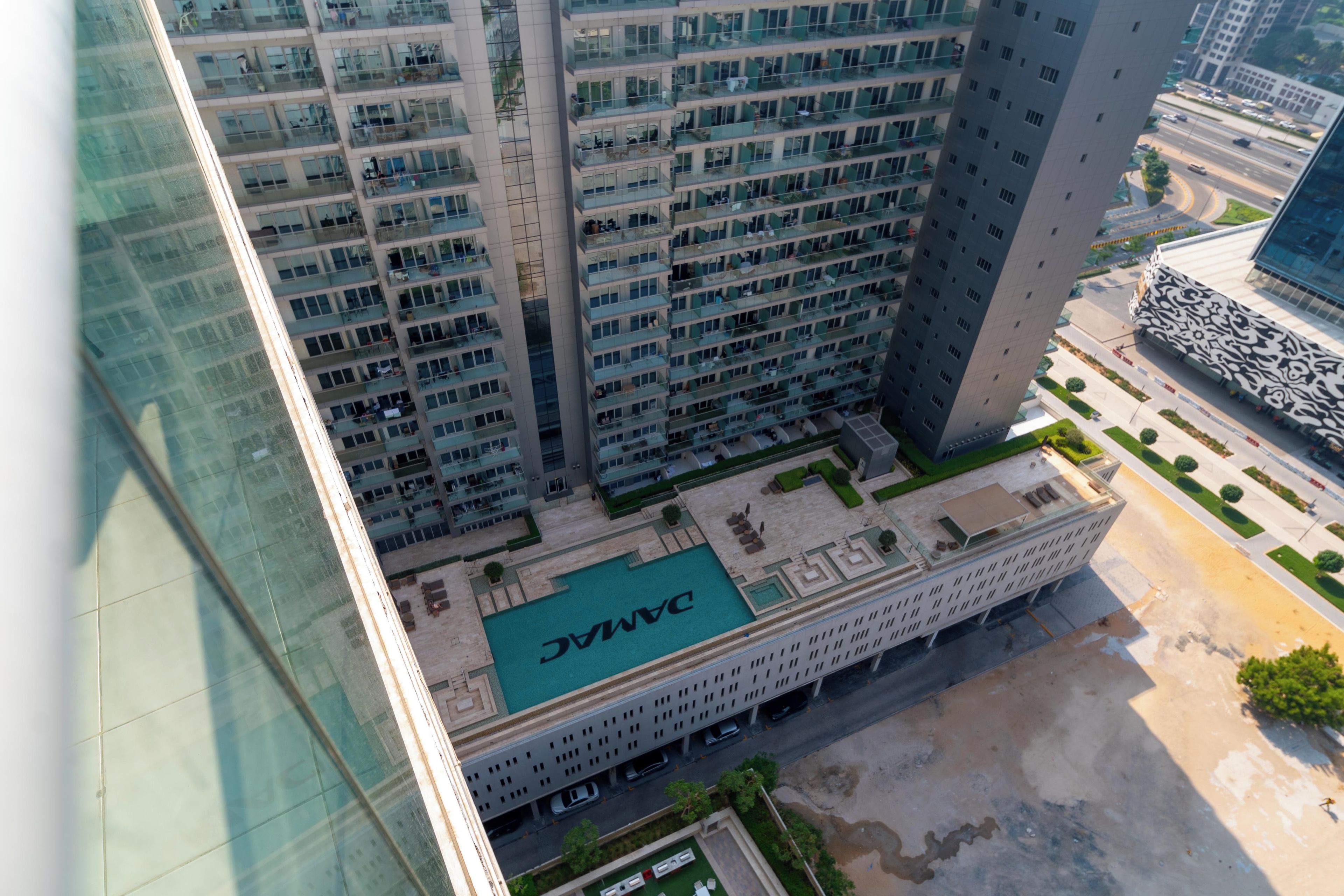 A high-rise building with multiple floors, a rooftop pool, and a parking area.