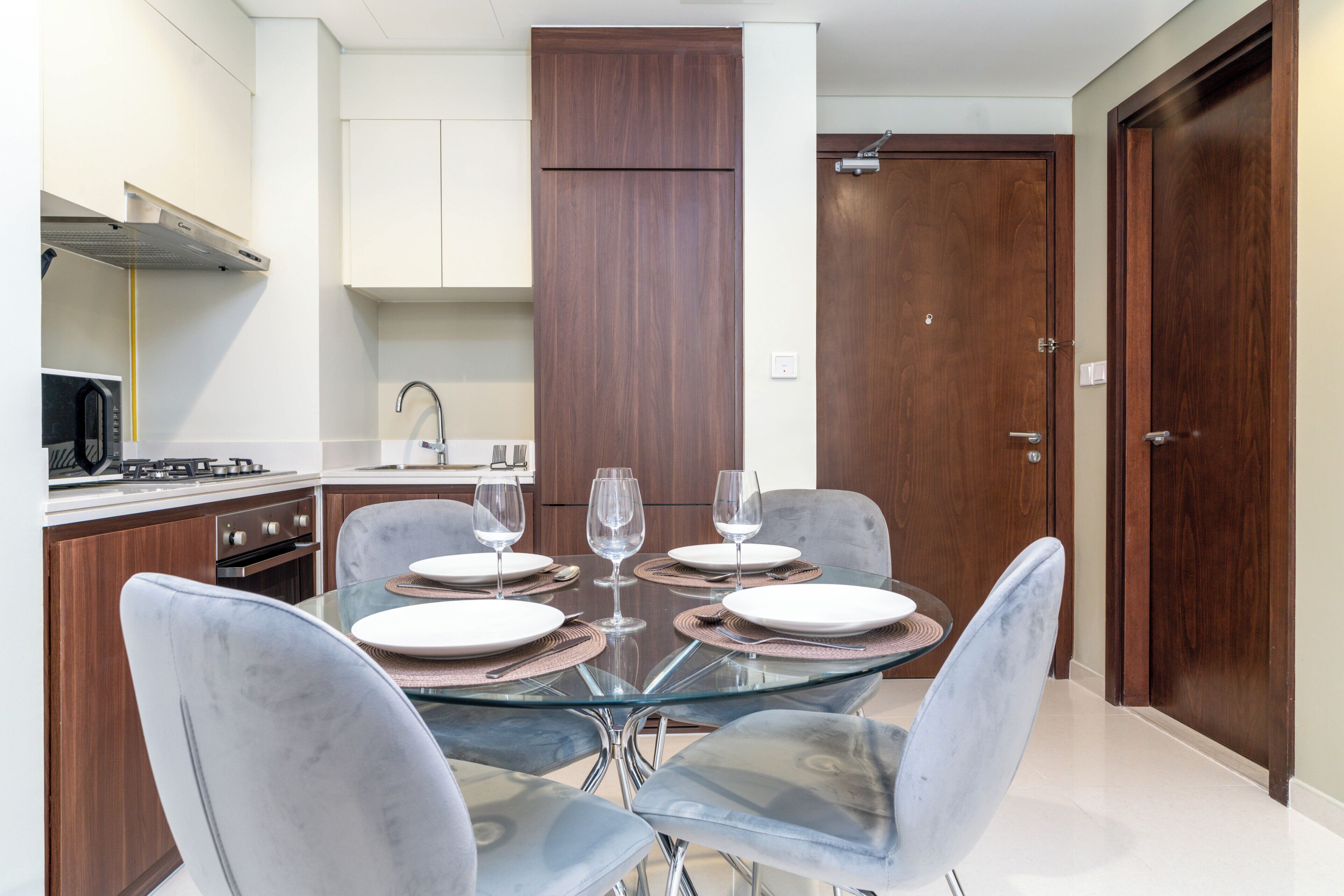 A modern kitchen with a dining table set for four, equipped with a gas stove, oven, and sink.