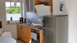 Een moderne keuken met een koelkast, oven en koffiezetapparaat.