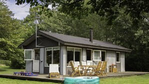 Eine kleine Holzhütte mit Veranda, Whirlpool und Gartenmöbeln.
