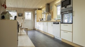 Eine moderne Küche mit weißen Schränken, einem eingebauten Backofen und einem Fenster mit Blick ins Freie.
