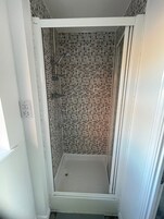 Una ducha con pared de azulejos y marco blanco.