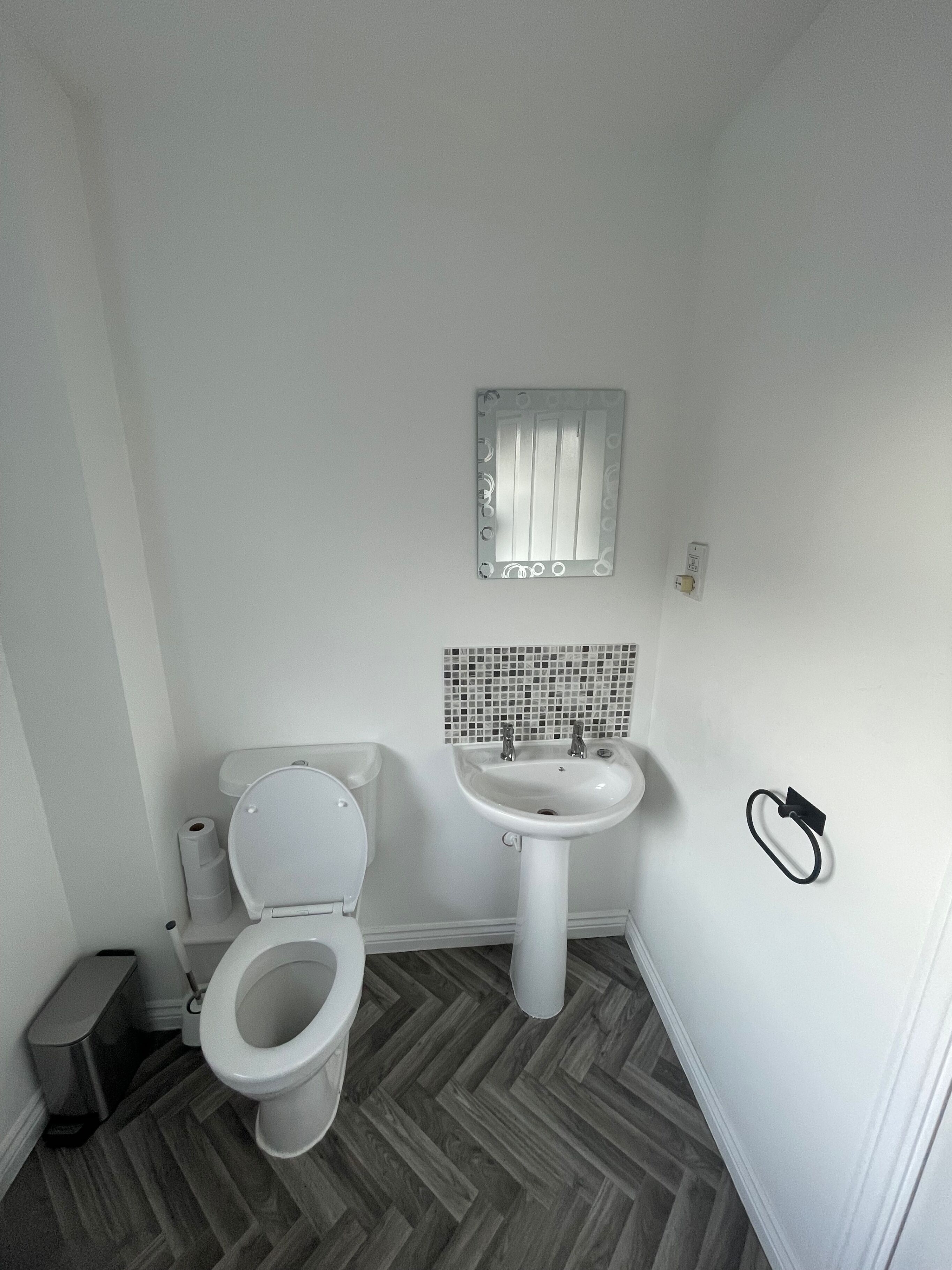 A bathroom with a toilet, sink, and mirror.