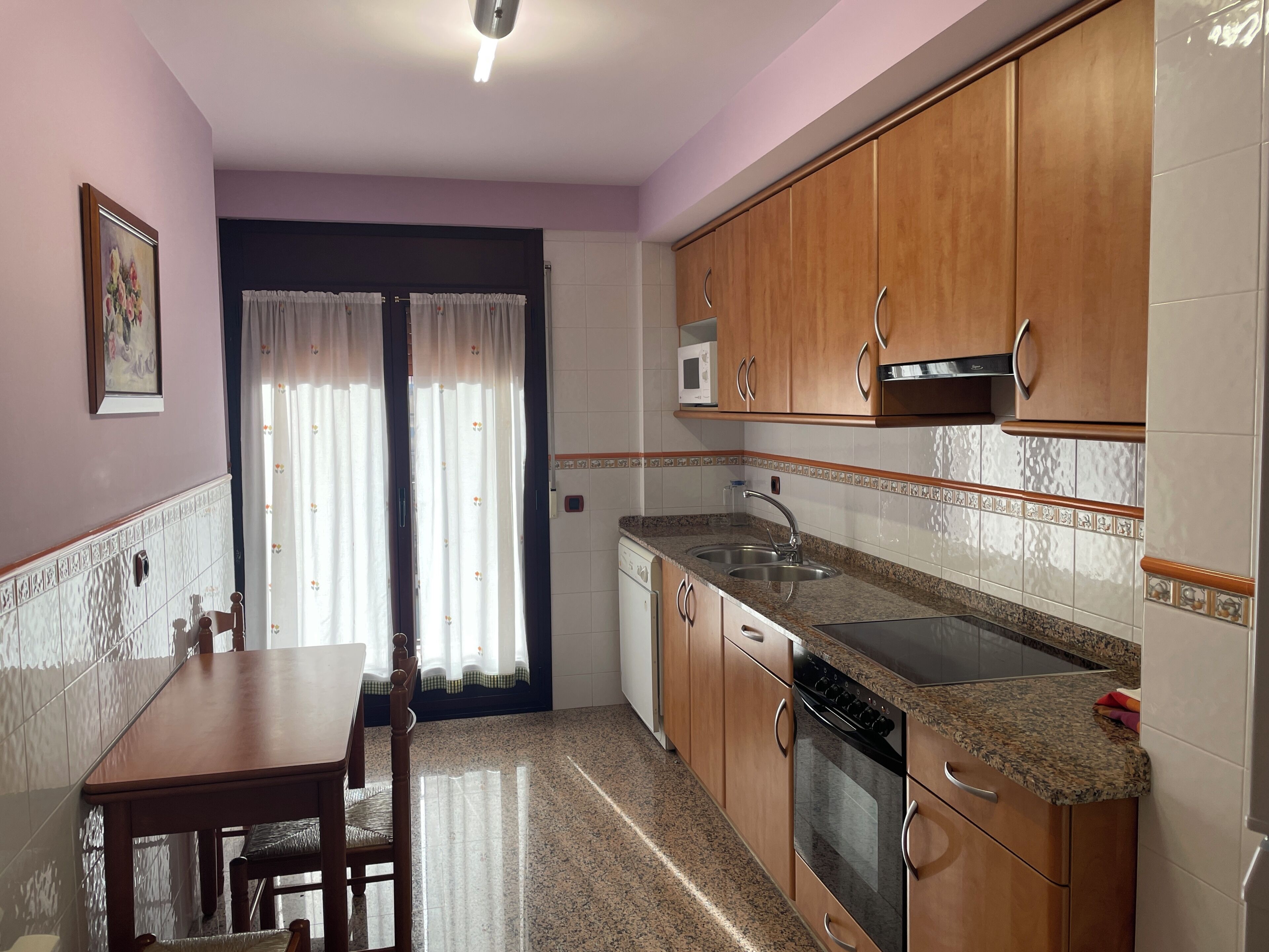 A kitchen with wooden cabinets, a granite countertop, a microwave, and a stove.