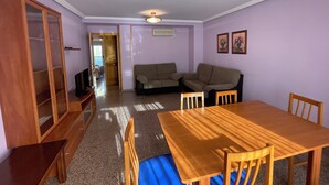 Ein Zimmer mit einem Holzesstisch, zwei Sofas, einem Holzschrank und einem Fernseher.