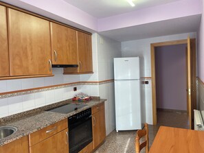 Une cuisine avec des meubles de rangement en bois, un réfrigérateur blanc, une cuisinière et une table à manger avec des chaises.