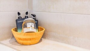 Eine Holtschale mit einer Shampooflasche und zwei Duschgels auf einem Badezimmerschrank.
